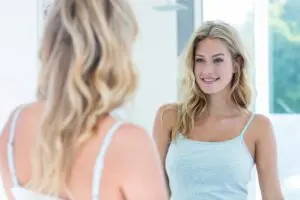 Smiling woman looking at herself in the bathroom