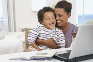 Mother and son at laptop laughing - Mommy Makeover