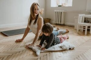 Drain free tummy tuck recovery concept. Woman doing yoga with her daughter to get fit after her tummy tuck.