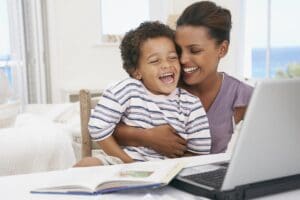 Mother and son at laptop laughing - Mommy Makeover
